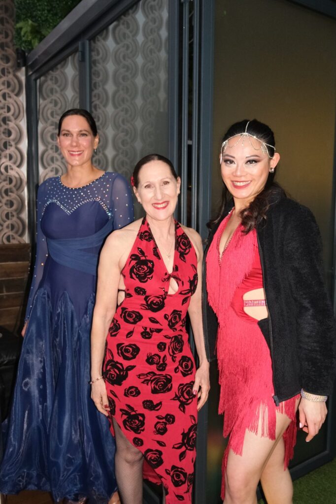 Three adult students in ballroom dresses at a Dance Amore event